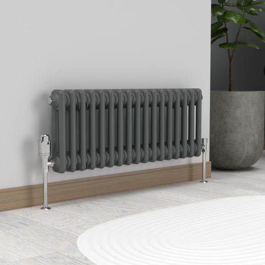 Anthracite grey horizontal two column radiator with chrome valves against a white wall