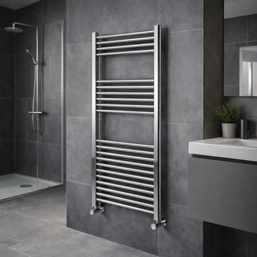 Chrome ladder towel radiator mounted on a grey tiled bathroom wall next to a walk-in shower